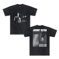 Black unisex garment-dyed cotton T-shirt by Johnny Huynh. Front: grayscale image of a person holding a flower, white text. Back: large JOHNNY HUYNH name with pronunciation, hand with flower, dotted pattern, and barcode design.