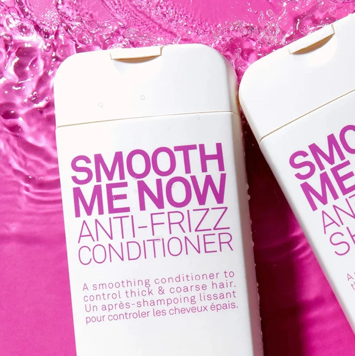 Two bottles of  Eleven Smooth Me Now Anti-Frizz Conditioner' on a pink background with water droplets.