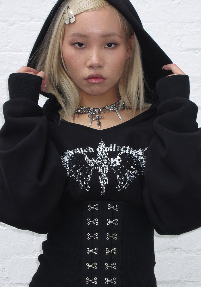 Model wearing a black hoodie featuring corset waist detailing and a custom logo design.