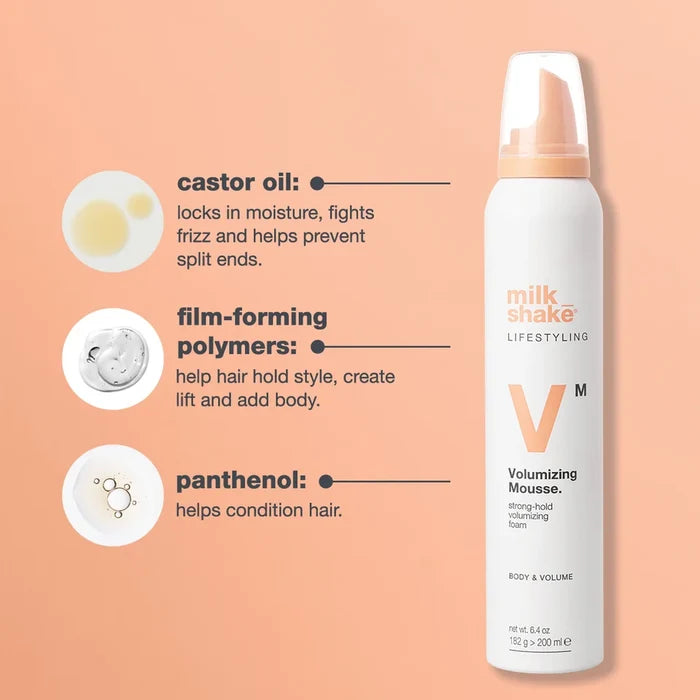 A white Milk Shake Volumizing Mousse can with a peach pump, shown on a peach background with ingredient callouts for castor oil, film-forming polymers, and panthenol.