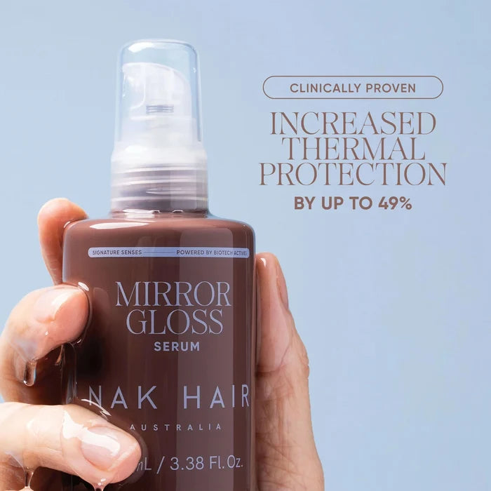 A hand holding a brown Mirror Gloss Serum bottle with water droplets dripping from the fingers, set against a light blue background with promotional text.