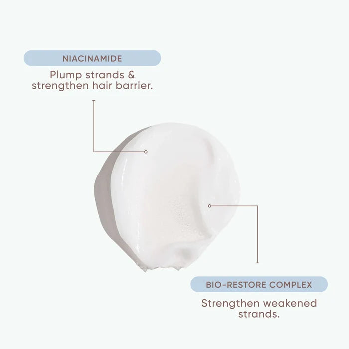 A white cosmetic smear on a very light gray background with callout labels reading 'NIACINAMIDE' and 'BIO-RESTORE COMPLEX' and short descriptive text about strengthening hair and weakened strands.