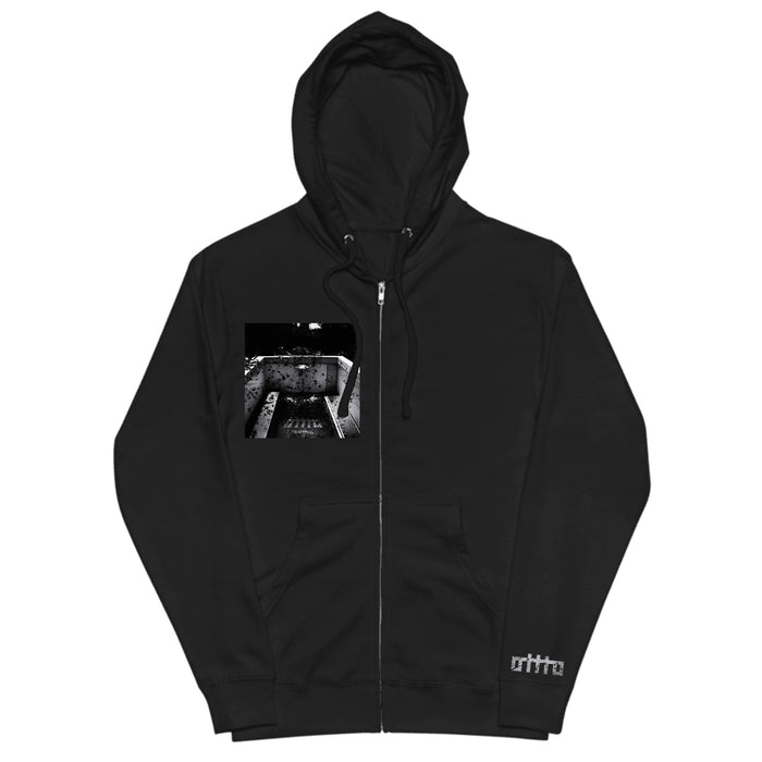 Black zip-up hoodie by OTTTO in premium Gildan Softstyle, featuring a white ortta logo near the hem and a black-and-white industrial print on the chest. Includes front zipper and drawstring hood. Available now for presale.