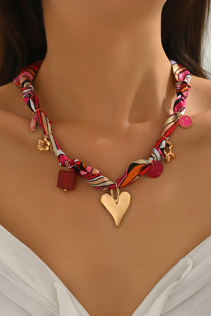 Strawberry pink printed knot scarf necklace with gold heart charm and multi detail accents, stylish Valentine accessory from The Pink Doxie Boutique.